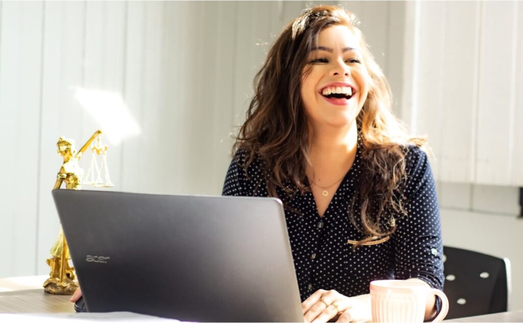 smiling girl infront of a laptop and working remotely in a digital workplace